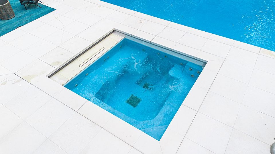 A small swimming pool is sitting next to a large swimming pool.