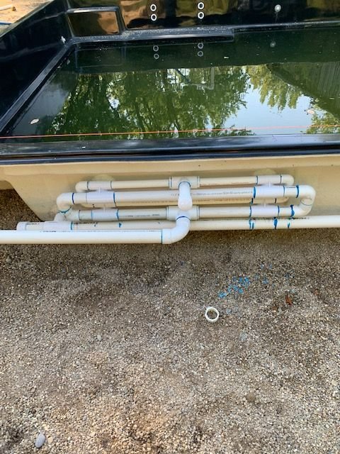 A swimming pool with a lot of pipes coming out of it.