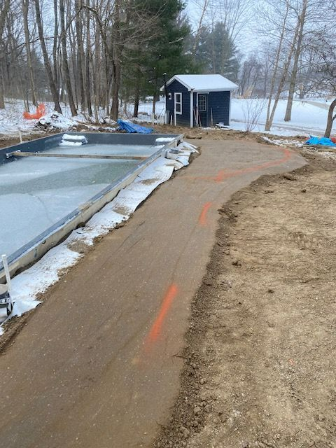 A dirt road leading to a shed in the snow.