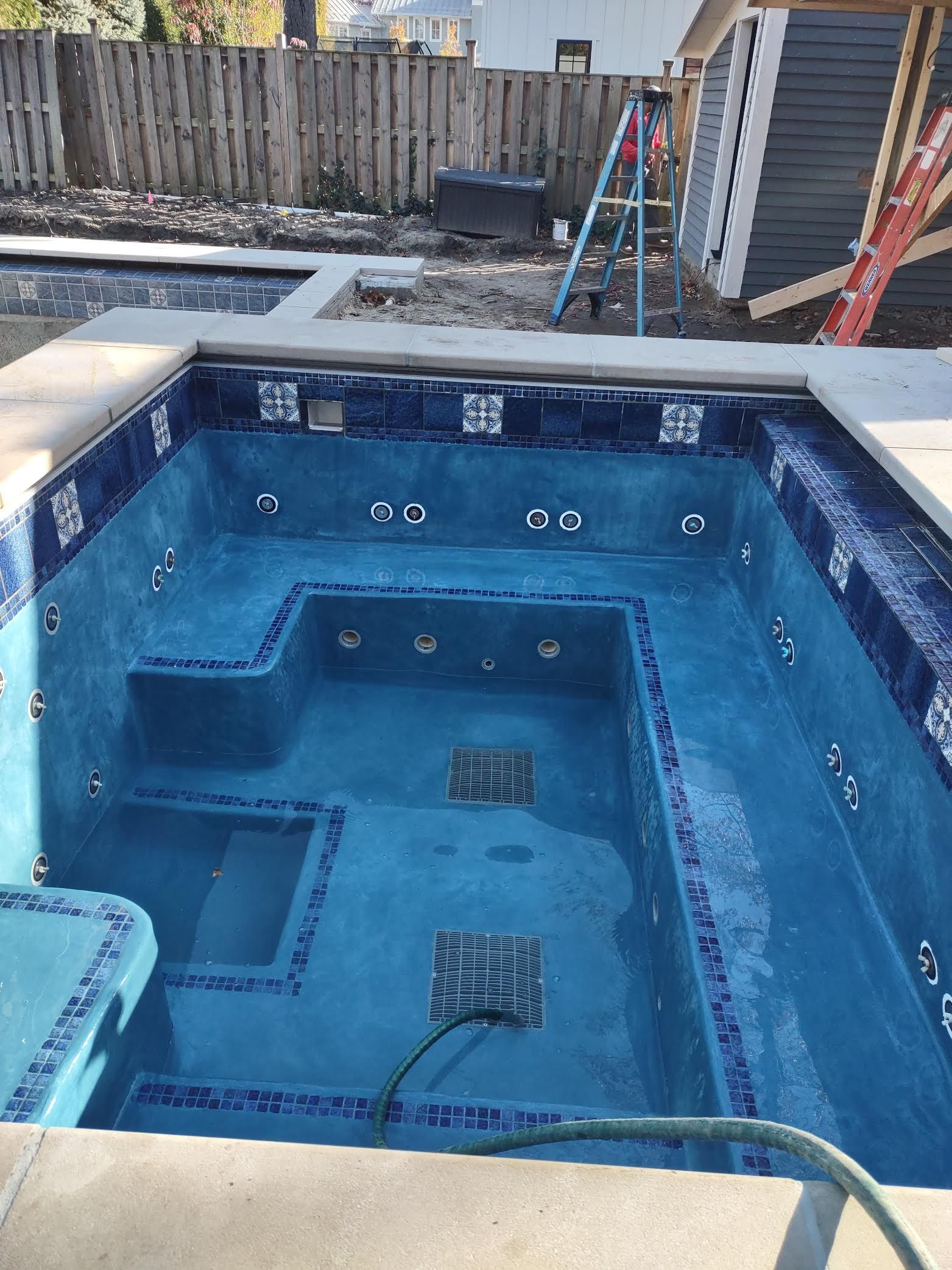 A large swimming pool with a hose attached to the side of it.