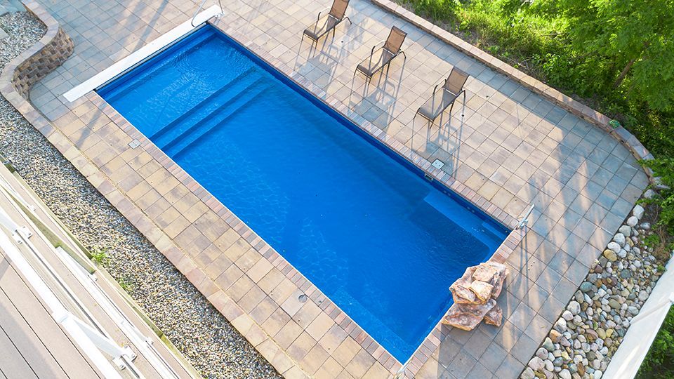 An aerial view of a large blue swimming pool surrounded by chairs.