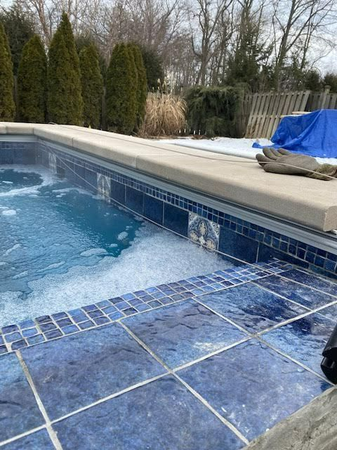 A swimming pool with blue tiles and a concrete border.