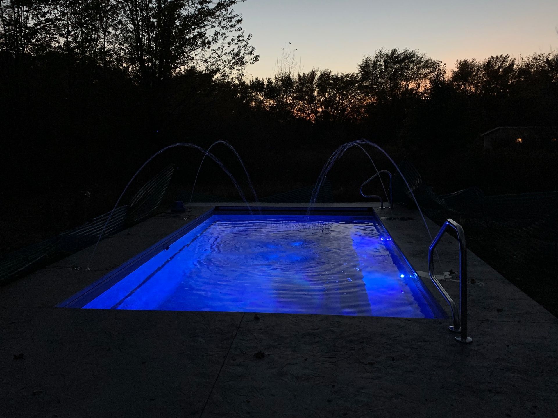 A swimming pool is lit up with blue lights at night.