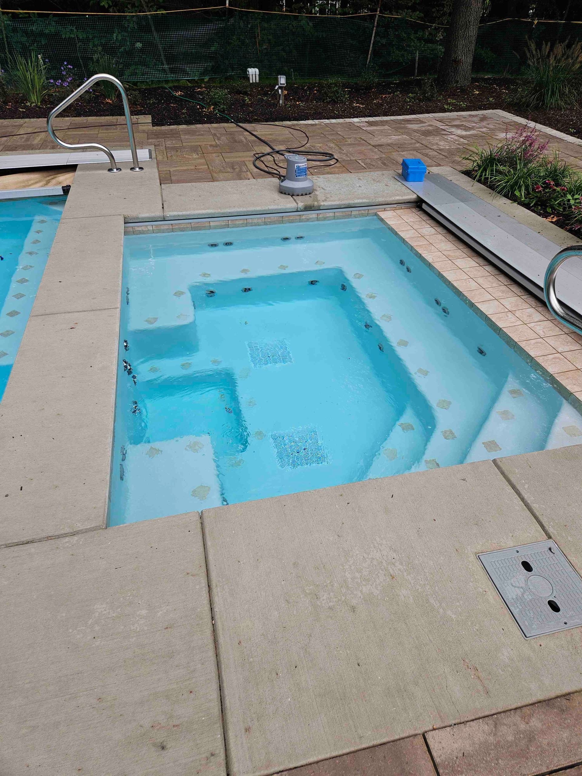 A small swimming pool with stairs and a cover on the side of it.