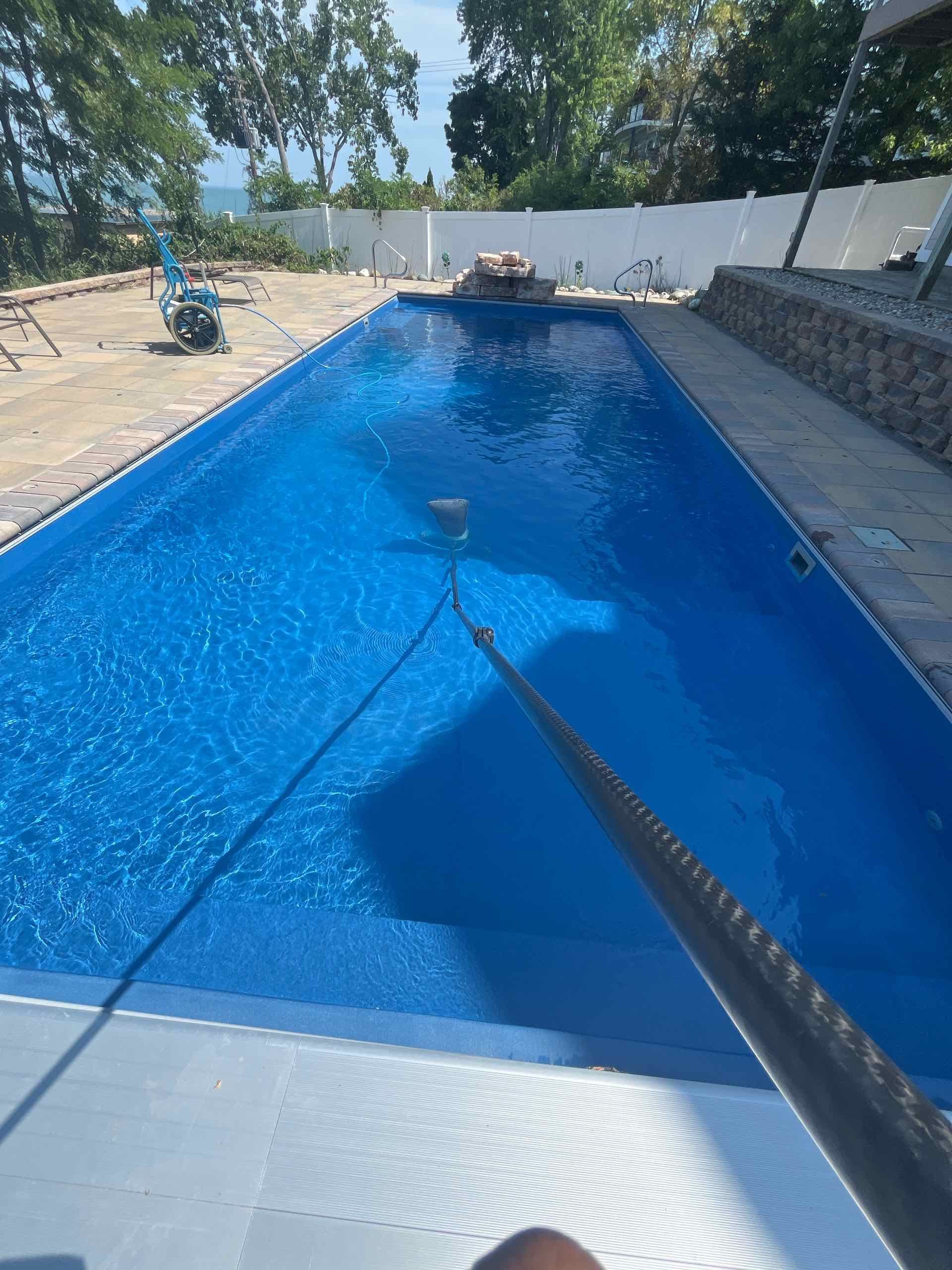 A person is taking a picture of a large blue swimming pool.