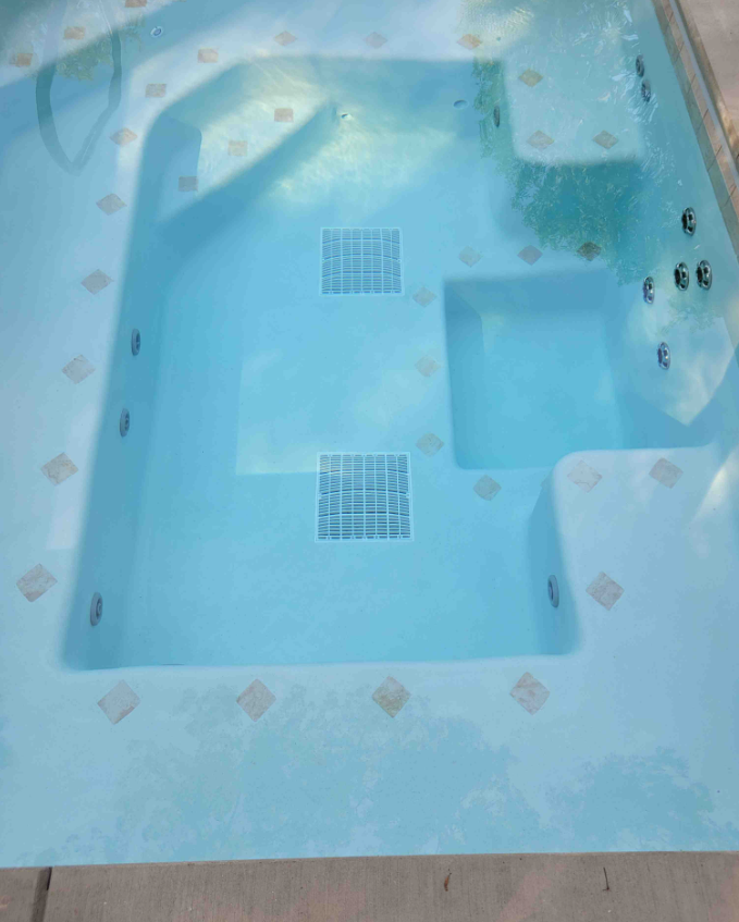 A large swimming pool with a jacuzzi in the middle of it.