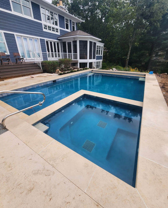A large swimming pool is in front of a large house.