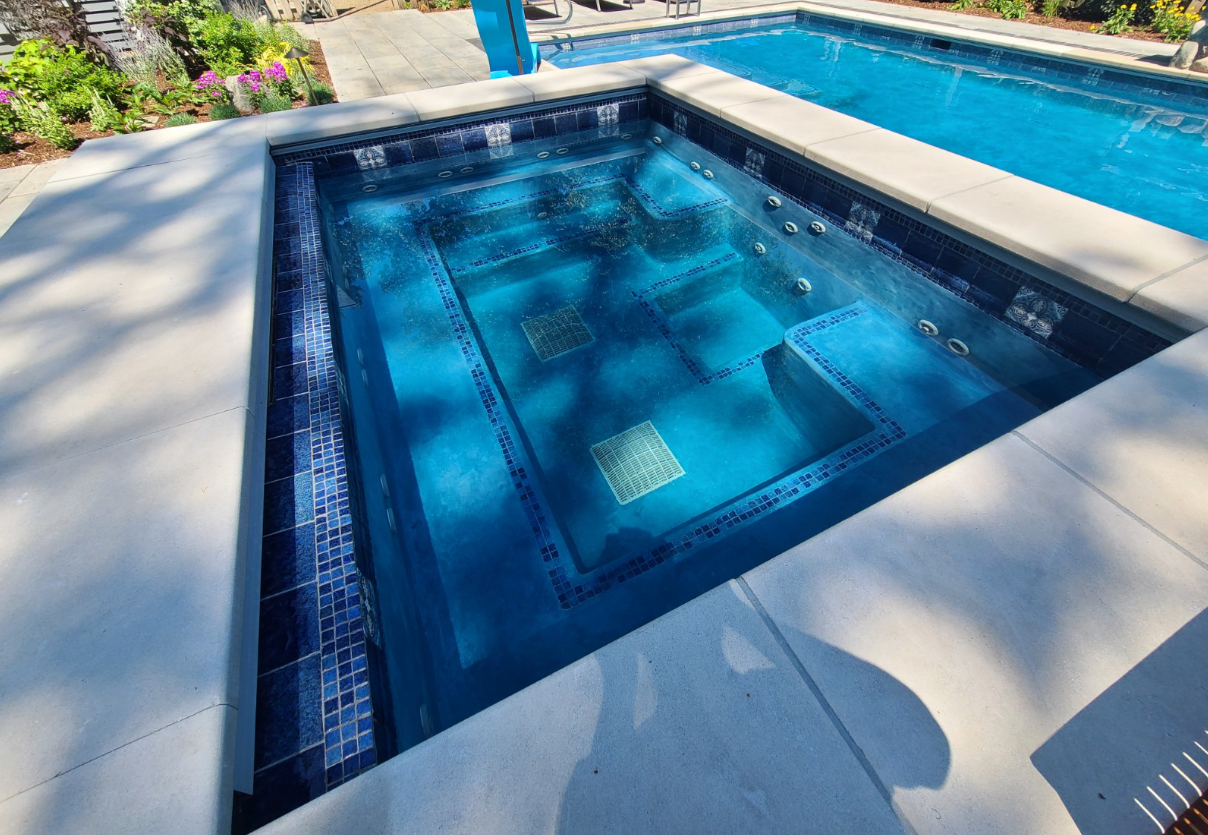 A large swimming pool with a hot tub in the middle of it.