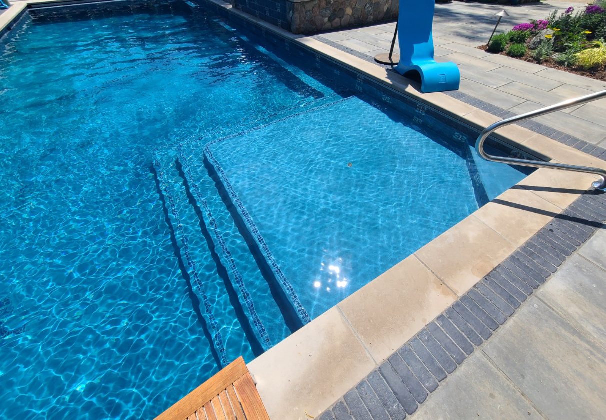 A large swimming pool with blue water and stairs leading to it.