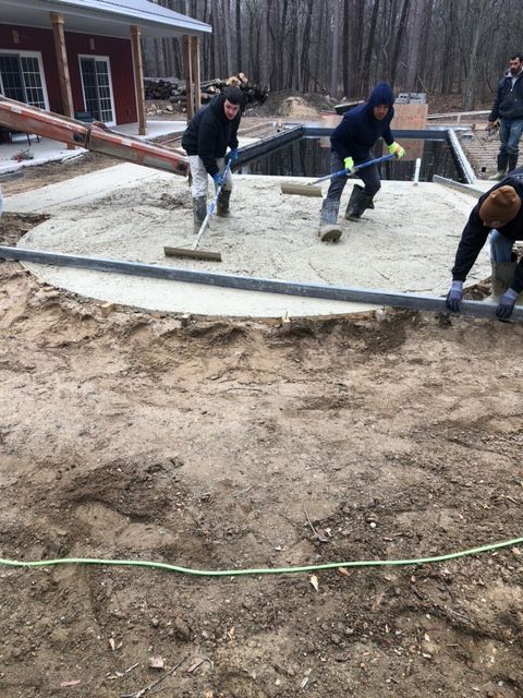 A group of men are working on a concrete patio.