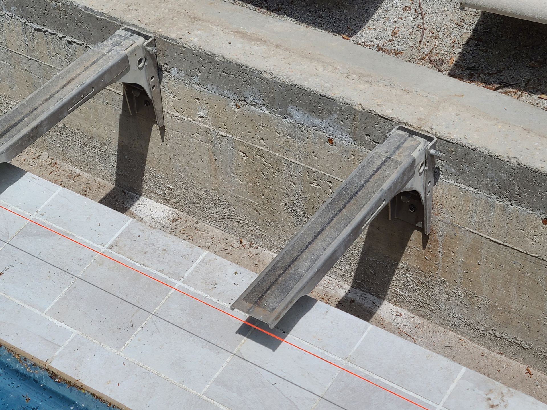A red line is being measured on the side of a swimming pool.
