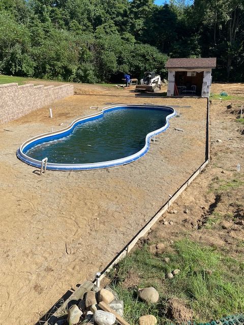A large swimming pool is being built in a backyard.