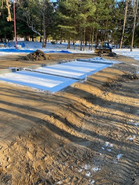 A lot of dirt and snow in a park with trees in the background.