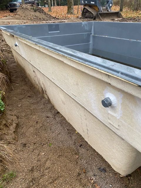 A large boat is sitting in the dirt next to a bulldozer.