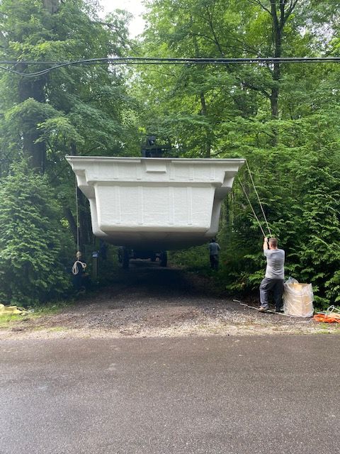A large white swimming pool is being lifted by a crane.
