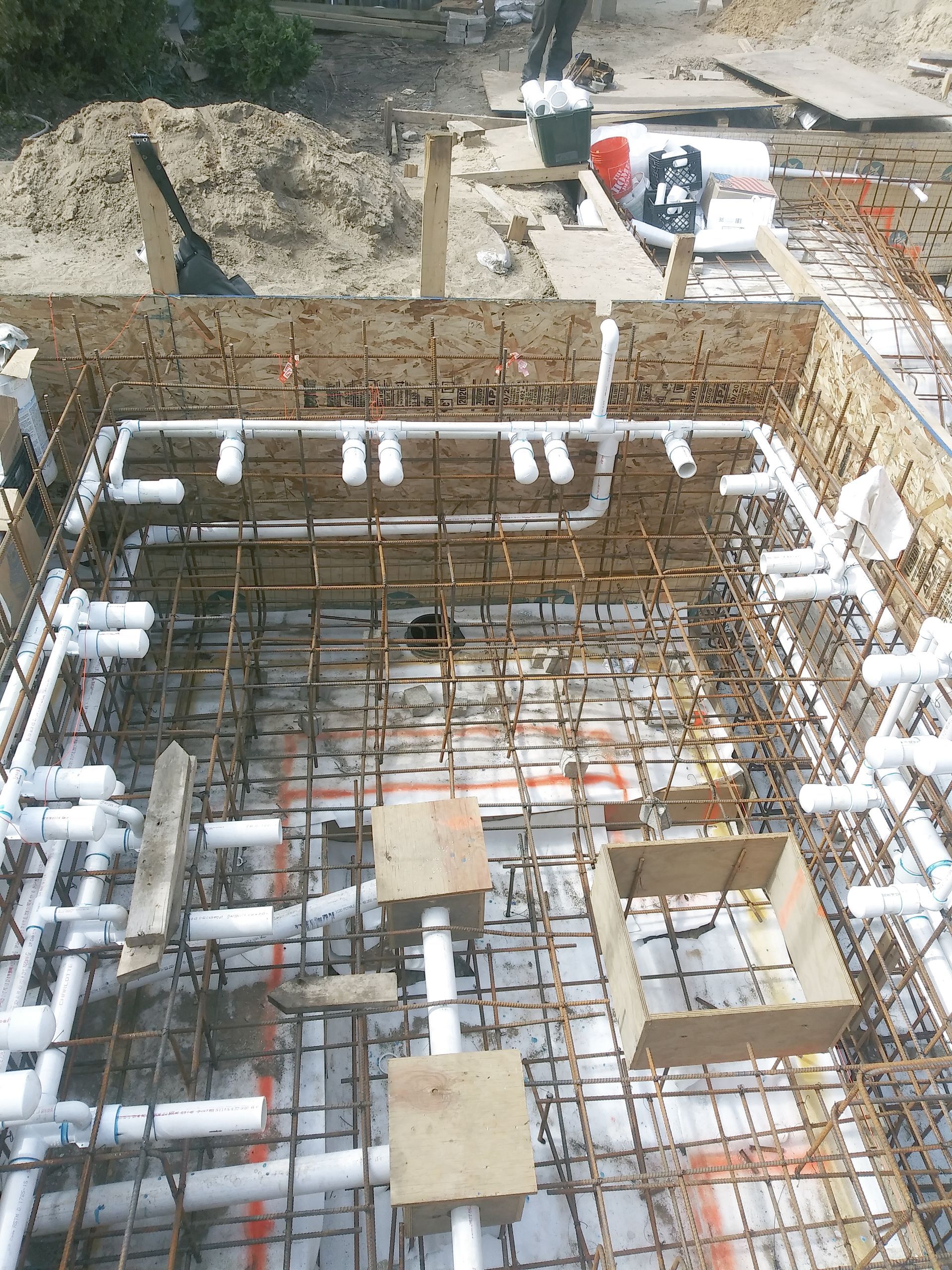 A swimming pool is being built with a lot of pipes.