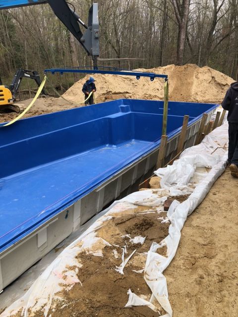 A large blue pool is being built in the dirt.