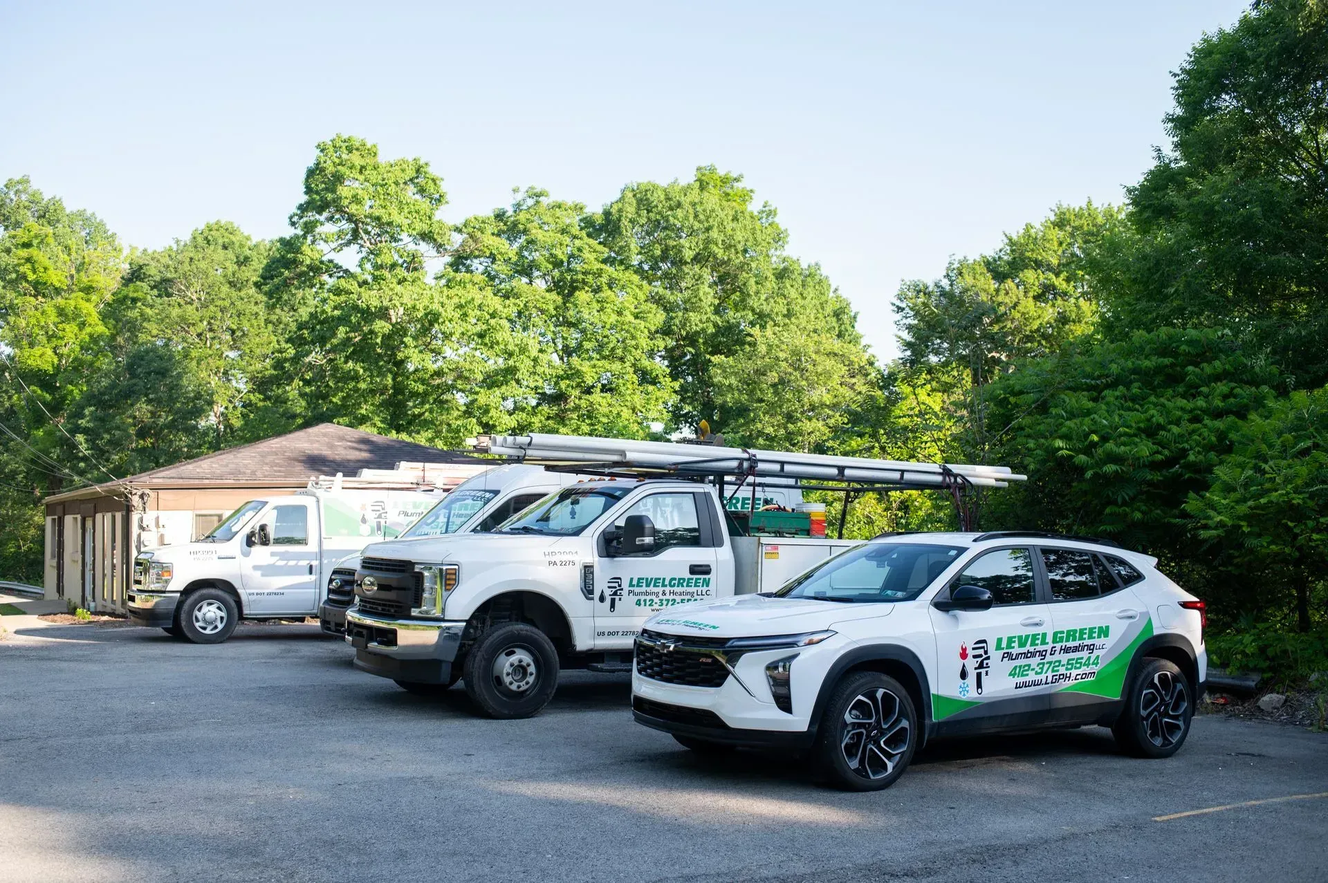 Three white work vehicles parked outside; logo on the side.