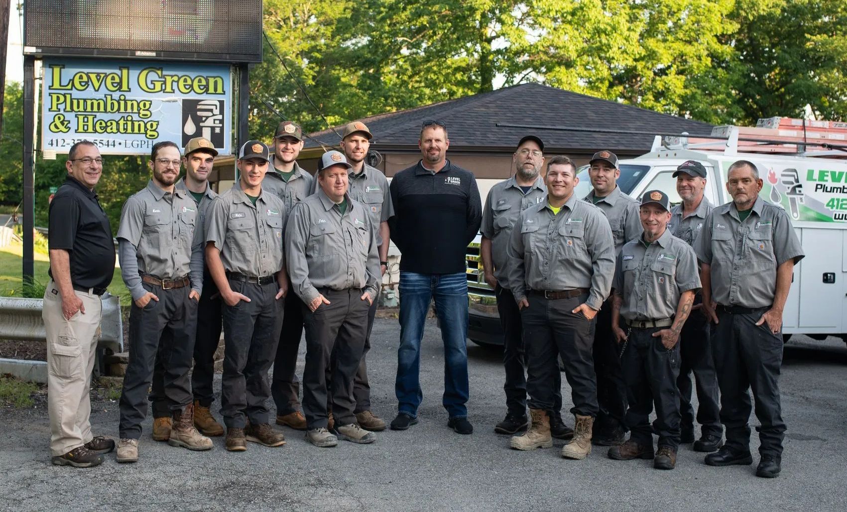 Group of plumbers in uniform posing outside their business.