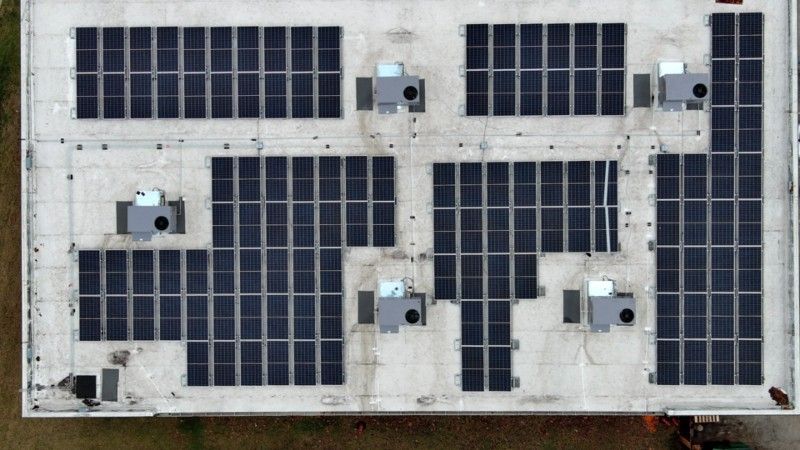An aerial view of a large building with solar panels on the roof.
