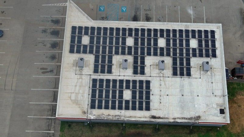 An aerial view of a building with solar panels on the roof.