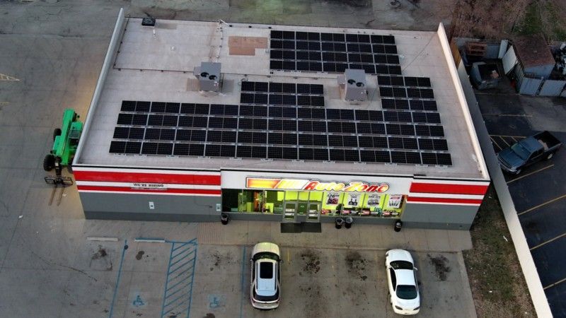 An aerial view of a convenience store with solar panels on the roof