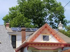 A house with solar panels on the roof and a tree in the background.