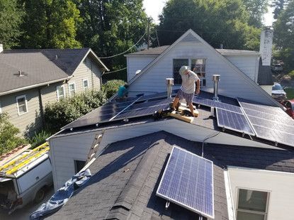 A man is installing solar panels on the roof of a house.