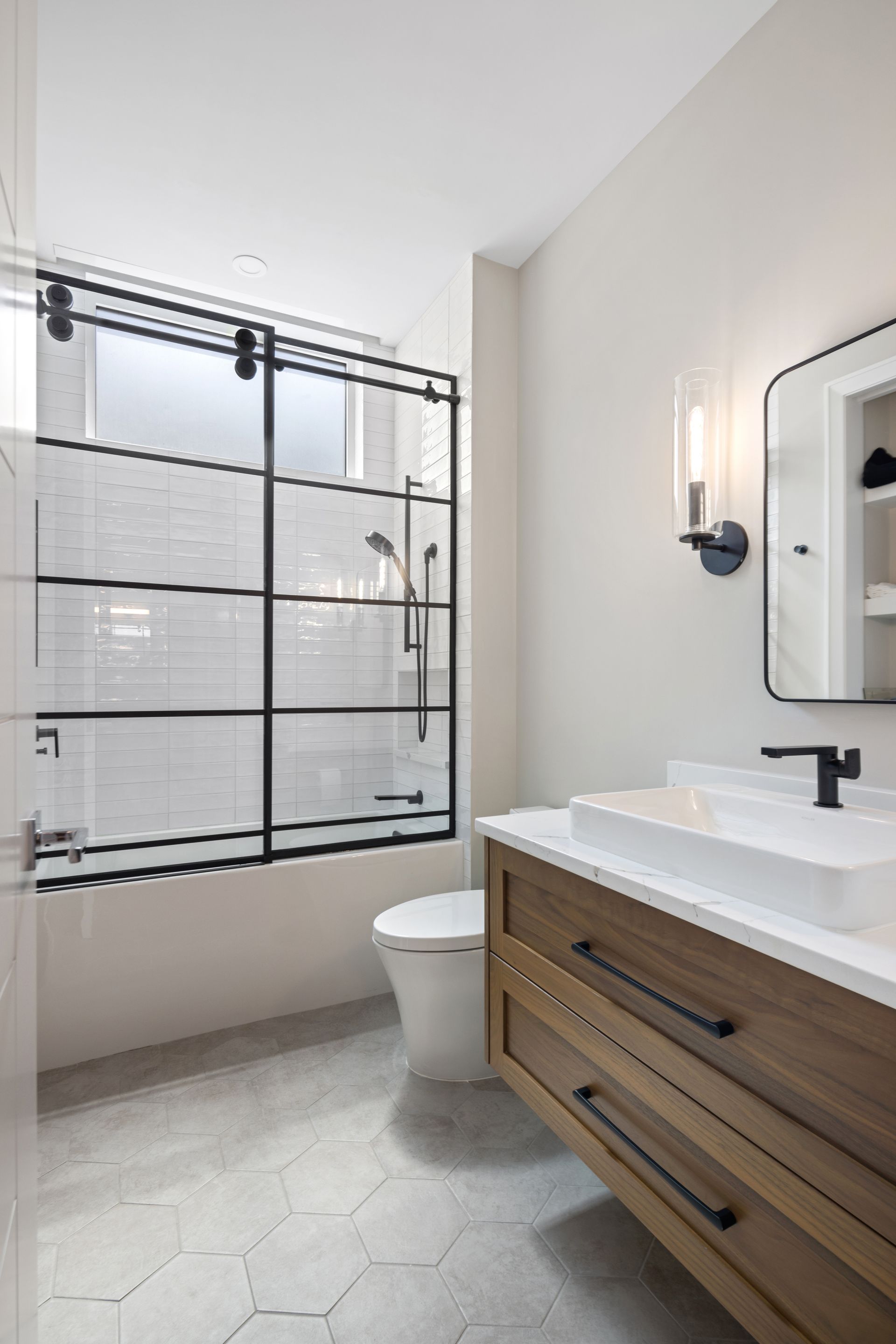 A bathroom with a toilet , sink , mirror and shower.