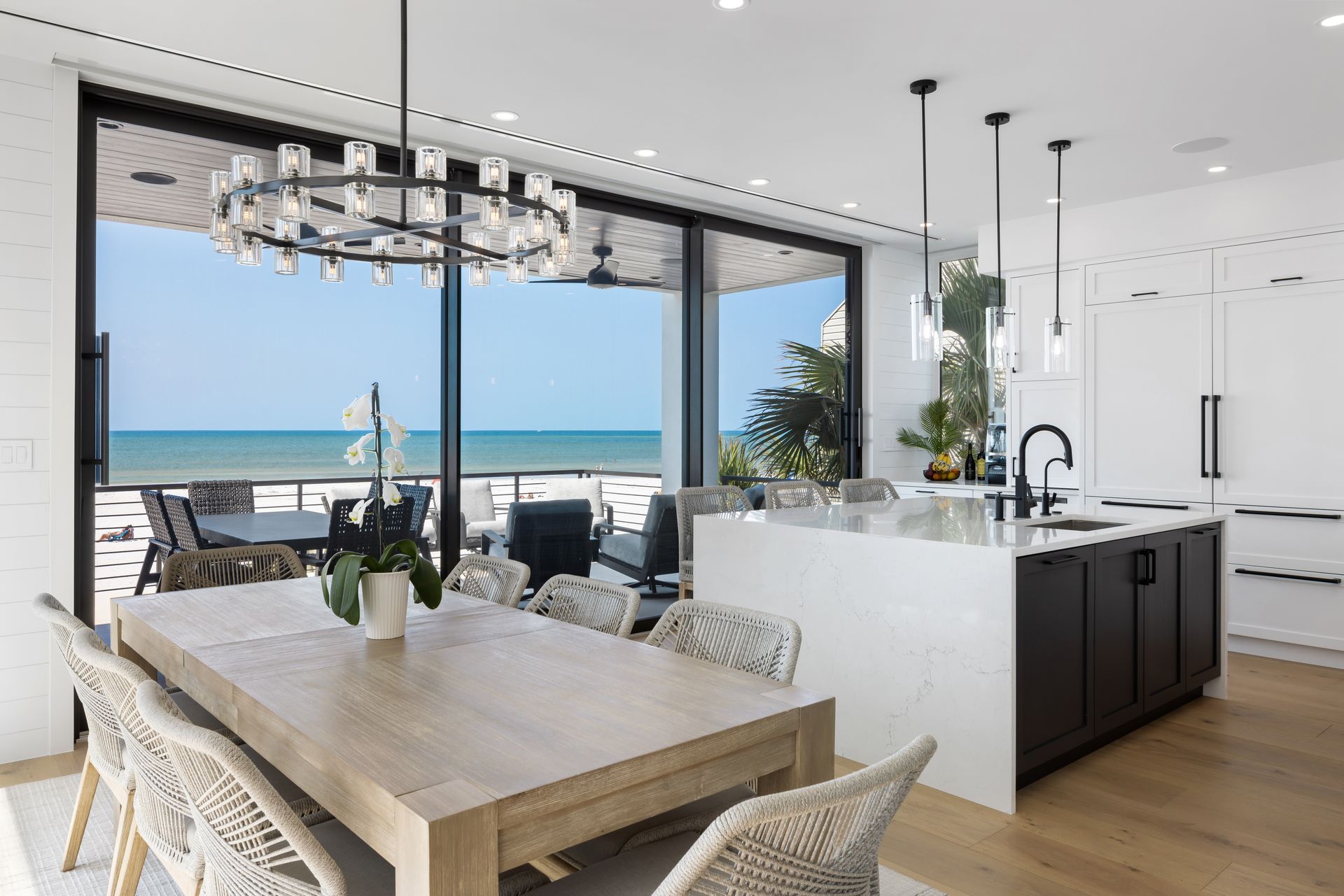 A dining room table and chairs in a kitchen with a view of the ocean.