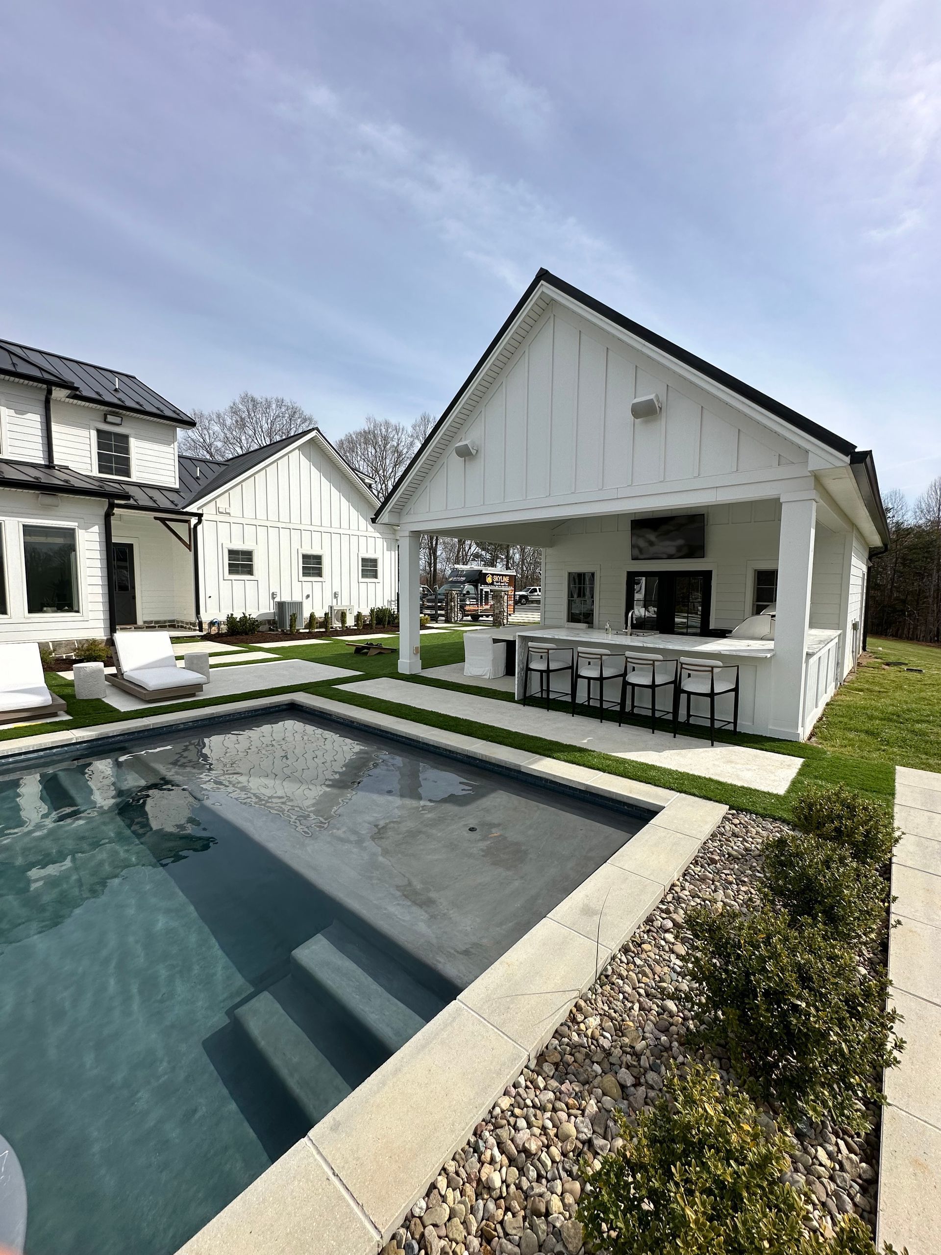 Outdoor pool and bar area with white structures and blue water.