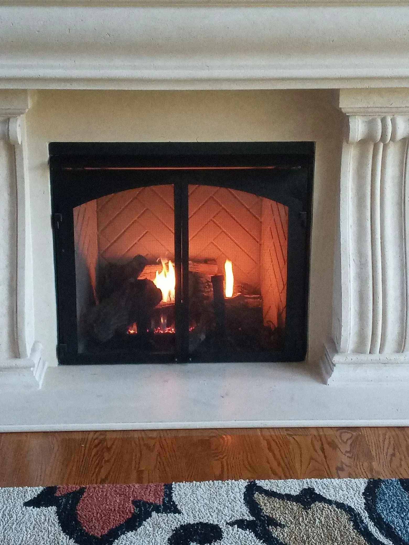 A fireplace with a fire burning inside, framed by a white mantelpiece.