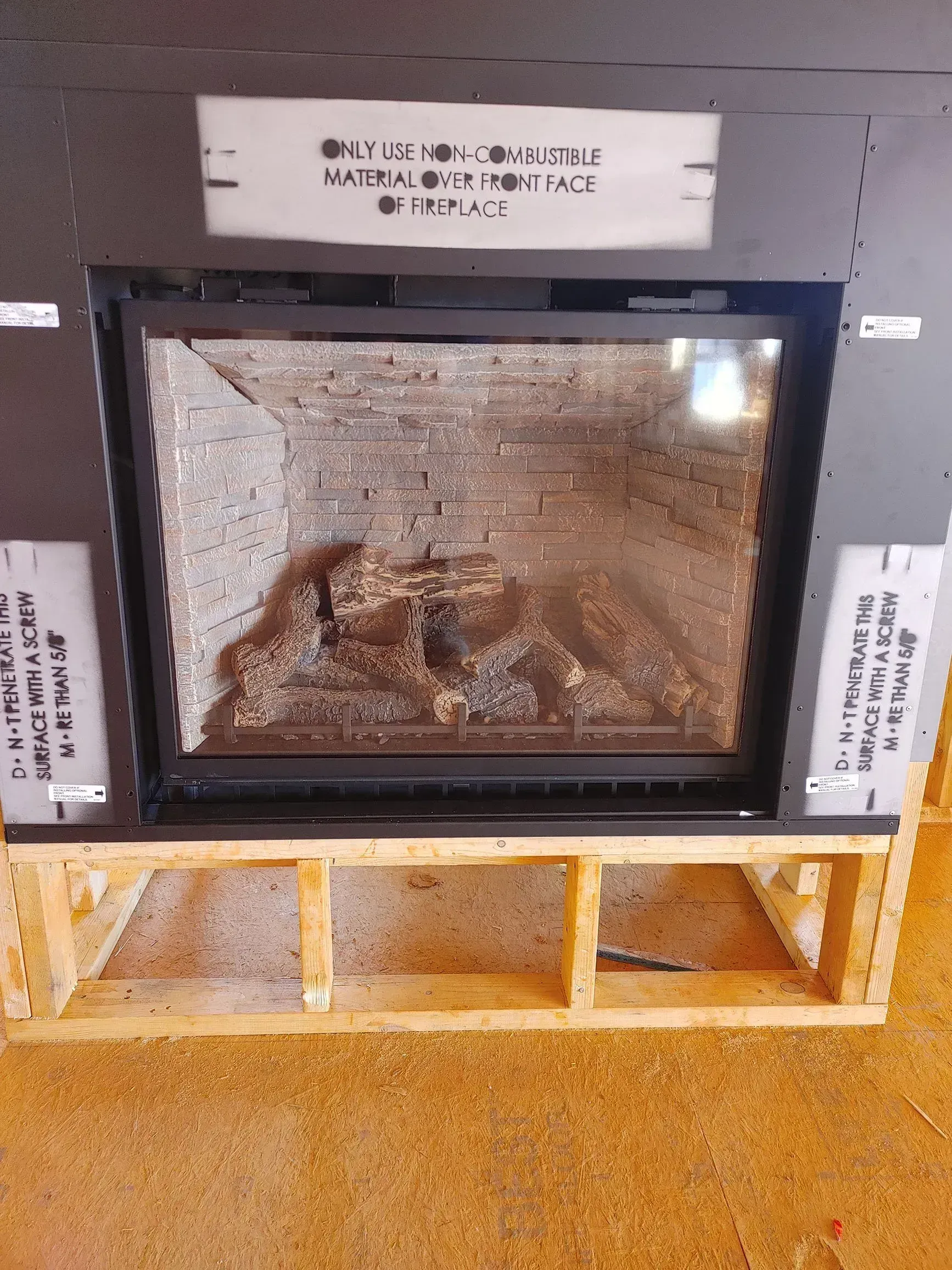 Fireplace with a black frame and a decorative log set against a brick interior.