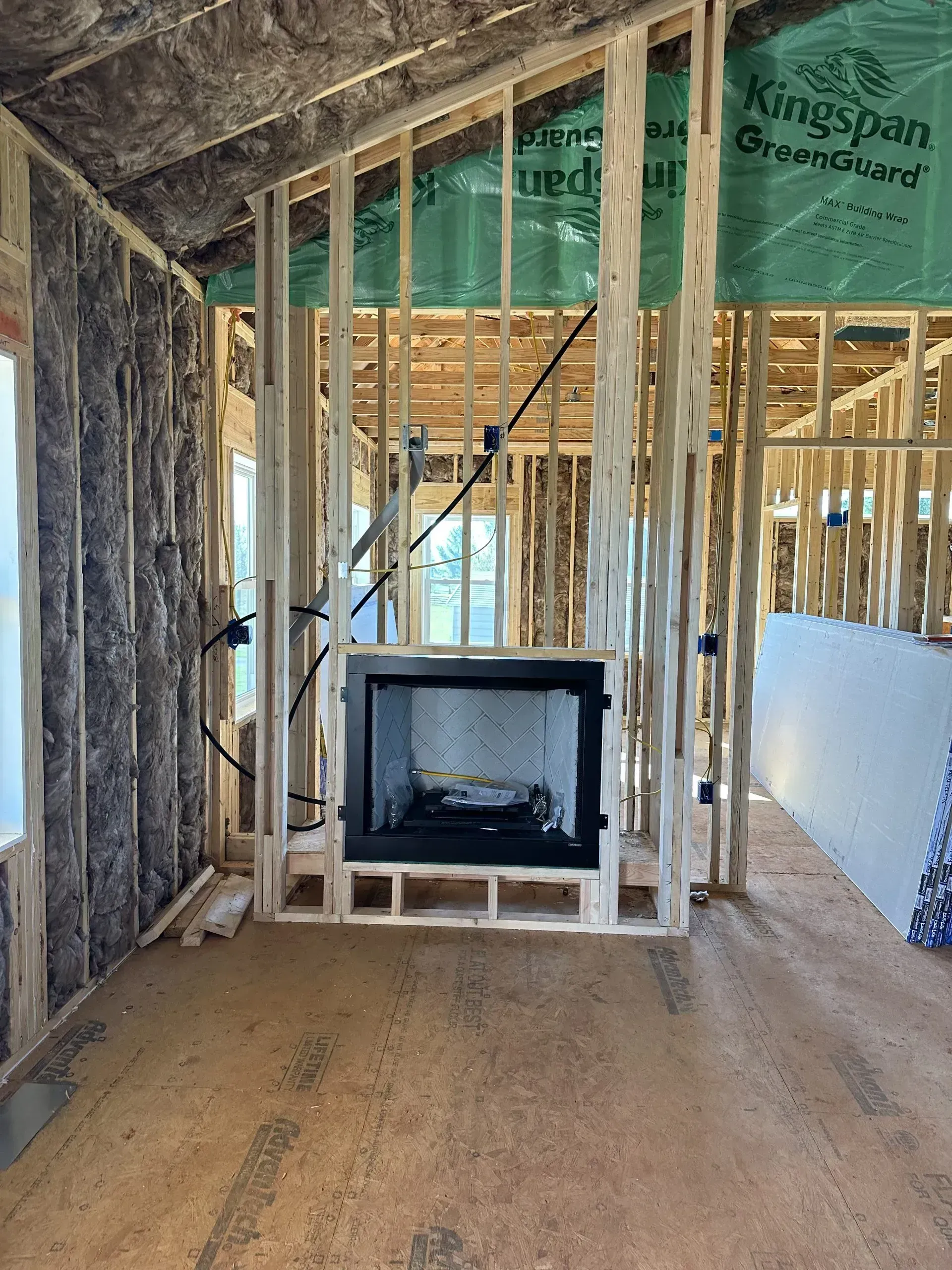 Interior framing of a house under construction with a fireplace and electrical wiring visible.