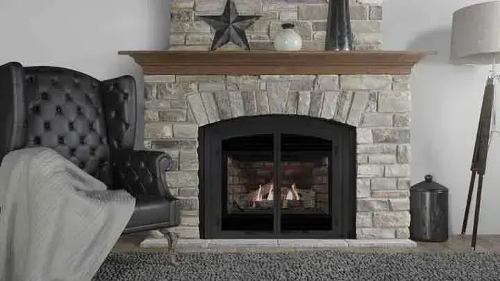 Cozy living room with fireplace. Black leather armchair, stone surround, wood mantel.