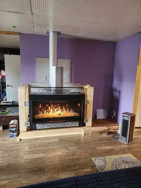 Electric fireplace with flame effect in a room with purple walls, wooden floor.
