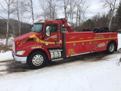 Red fire rescue truck parked on a snowy roadside in a wooded area