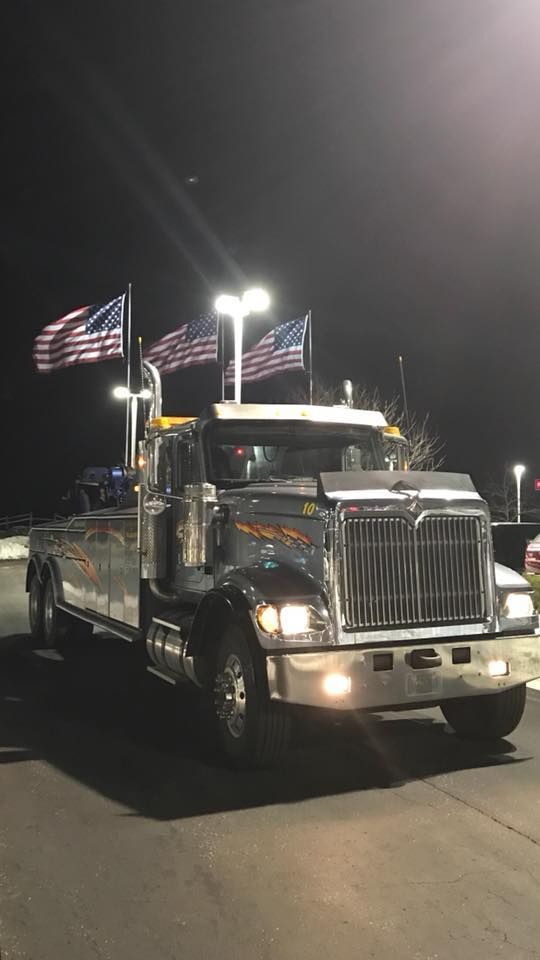 Chrome semi-truck at night with American flags parked under bright lights