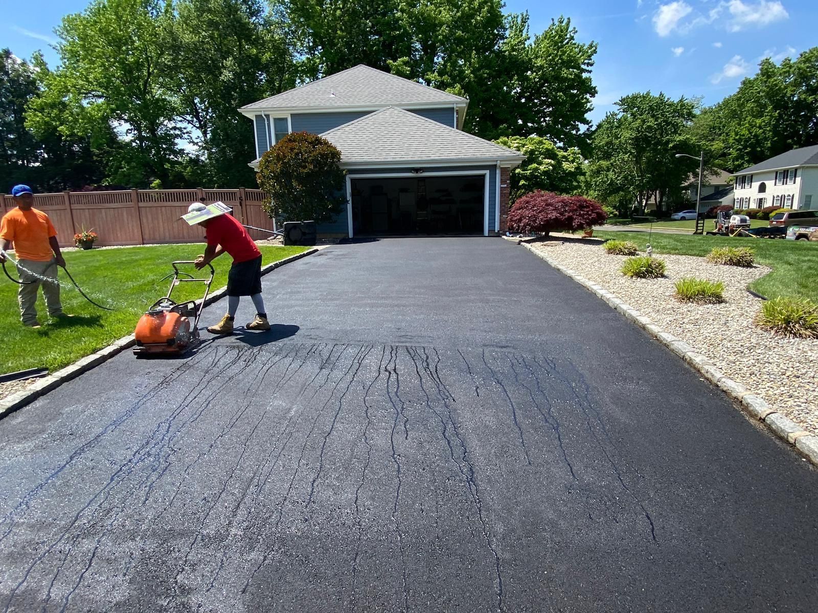 A man is mowing a driveway in front of a house
