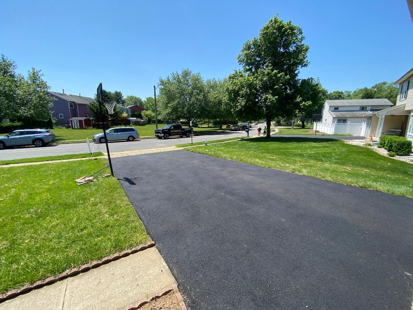 A driveway in a residential neighborhood with cars parked on the side of it.