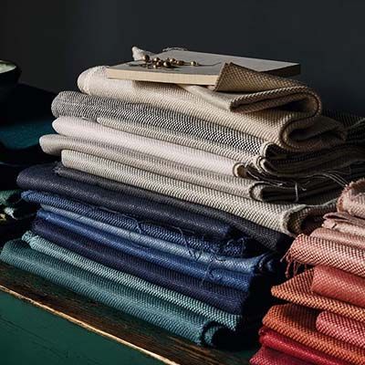 Pile of colorful fabric samples, stacked on a green surface.