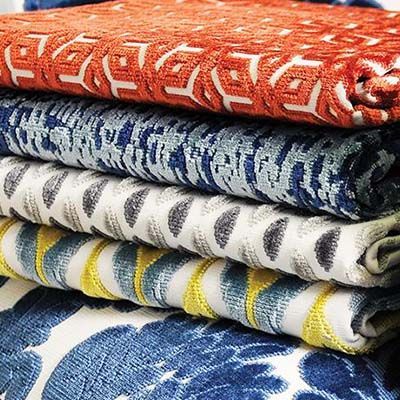 Pile of folded patterned fabric in orange, blue, gray, and yellow.