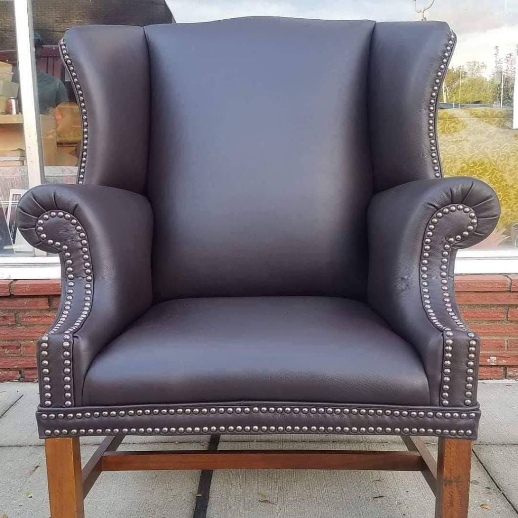 Brown leather wingback chair with nailhead trim.