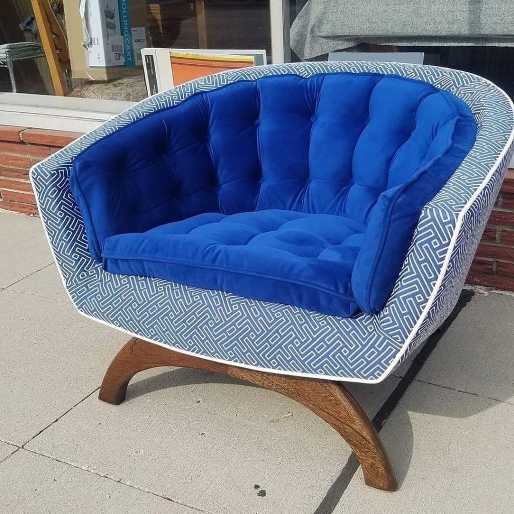 Blue tufted armchair with patterned exterior, on curved wooden legs, outdoors.