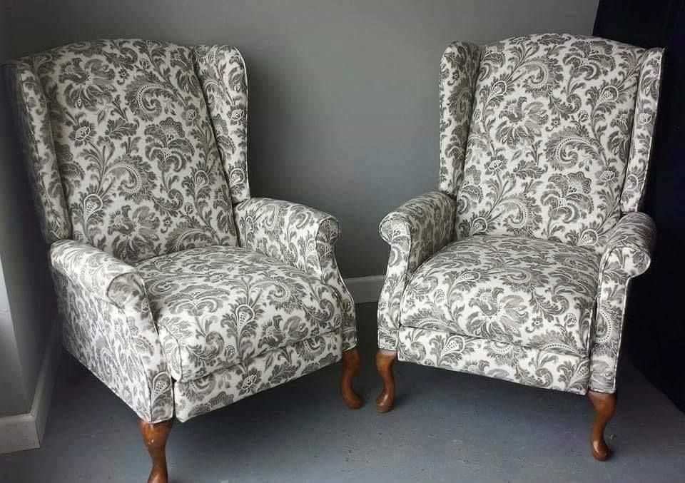 Two upholstered wingback chairs with gray and white patterned fabric against a gray wall.