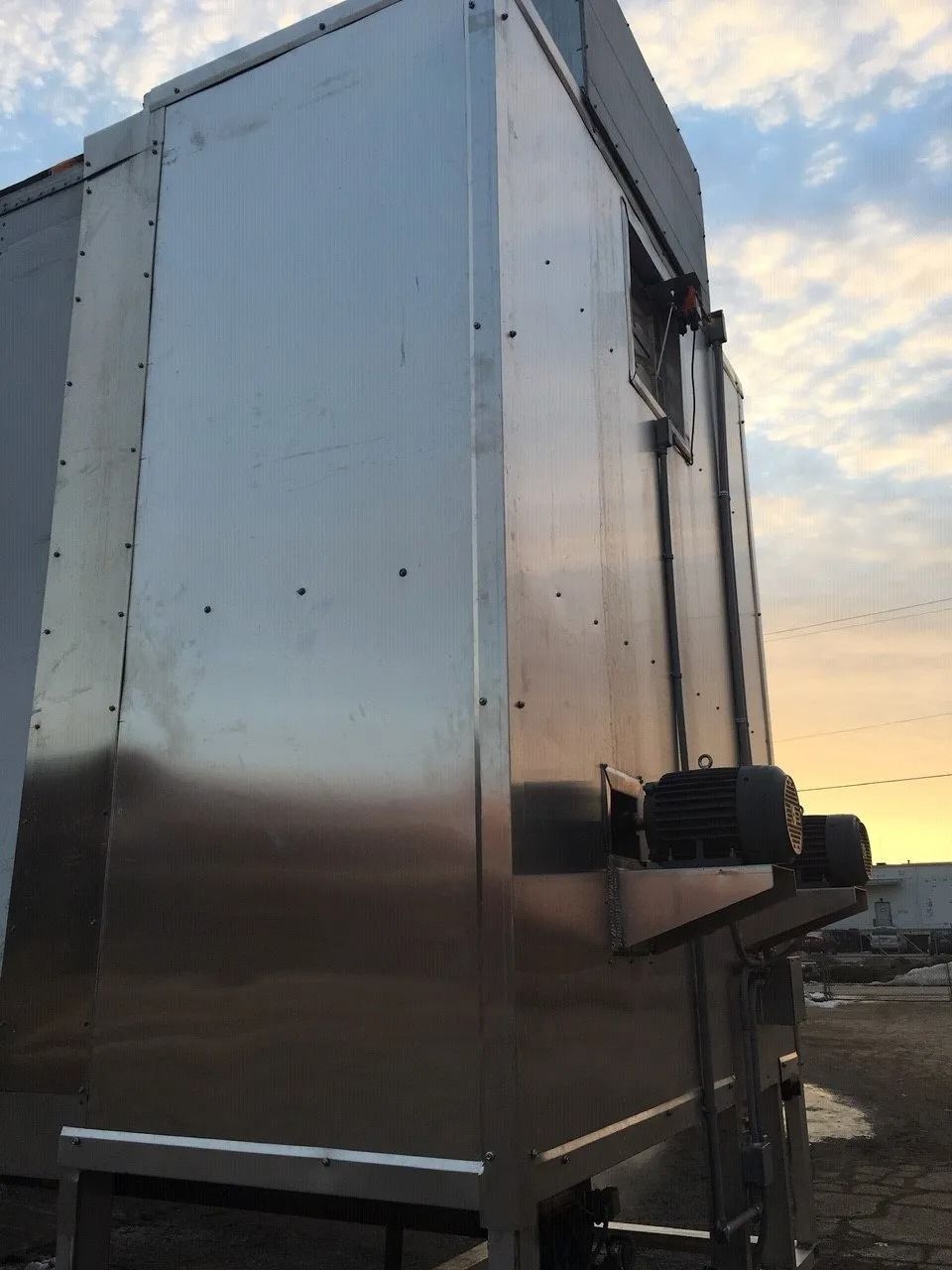 Stainless steel food trailer parked outdoors at sunset