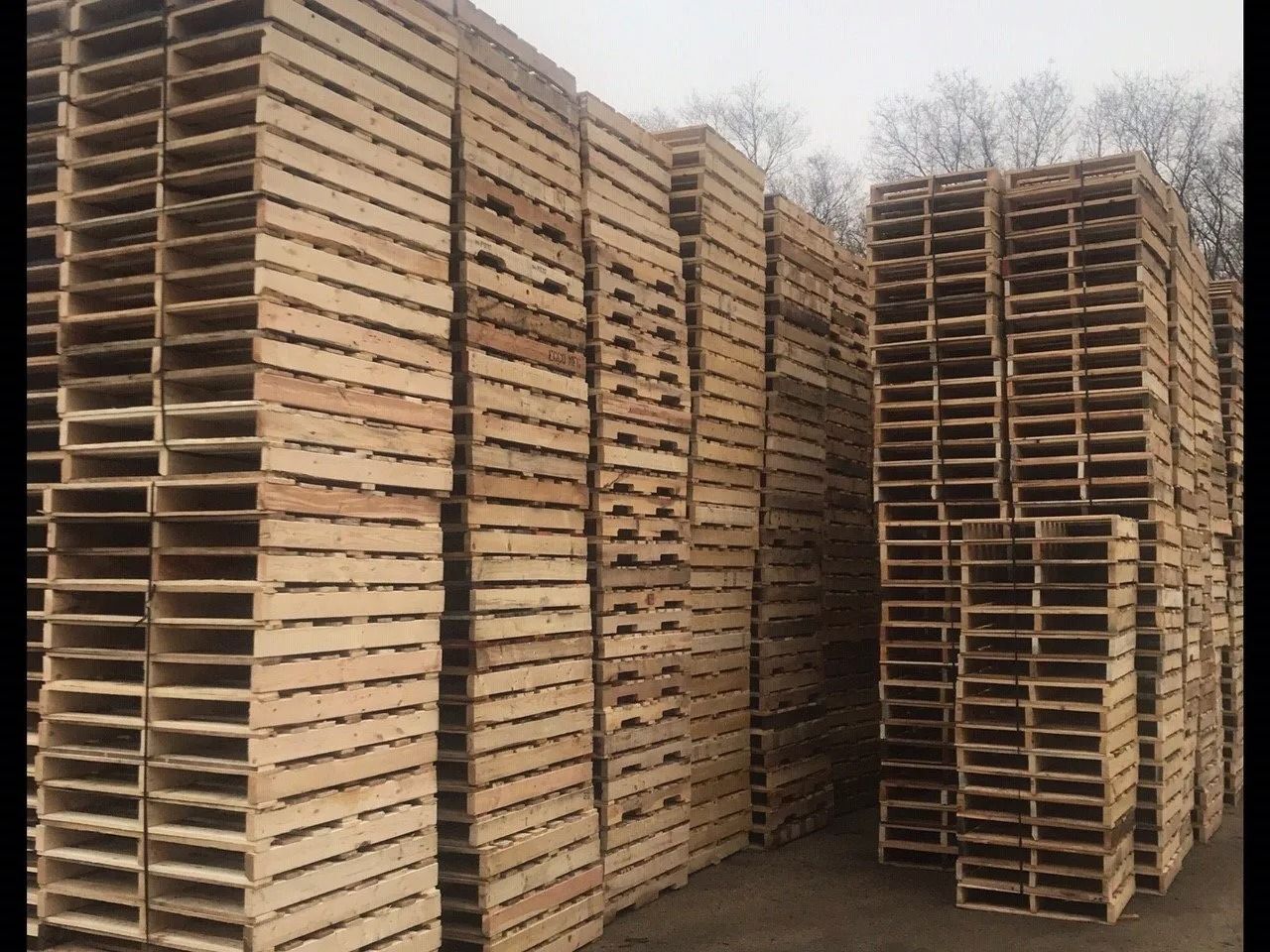 Stacks of wooden pallets piled high outdoors in a foggy storage yard