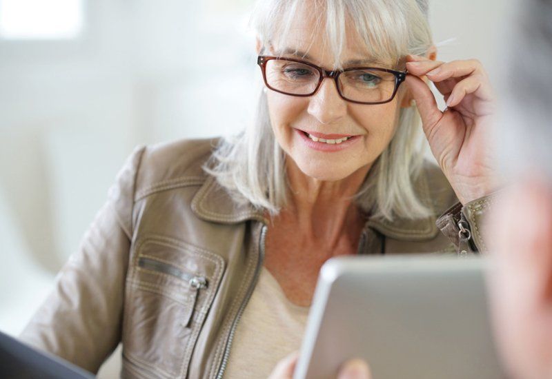 Senior woman in optical store trying eyeglasses on
