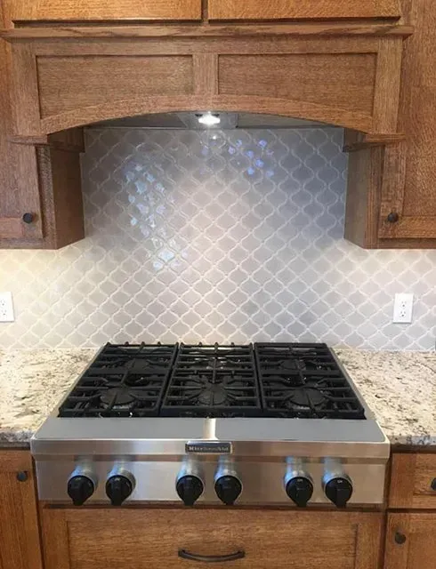 Kitchen with wooden cabinets, a gas stove, granite countertop, and decorative backsplash.