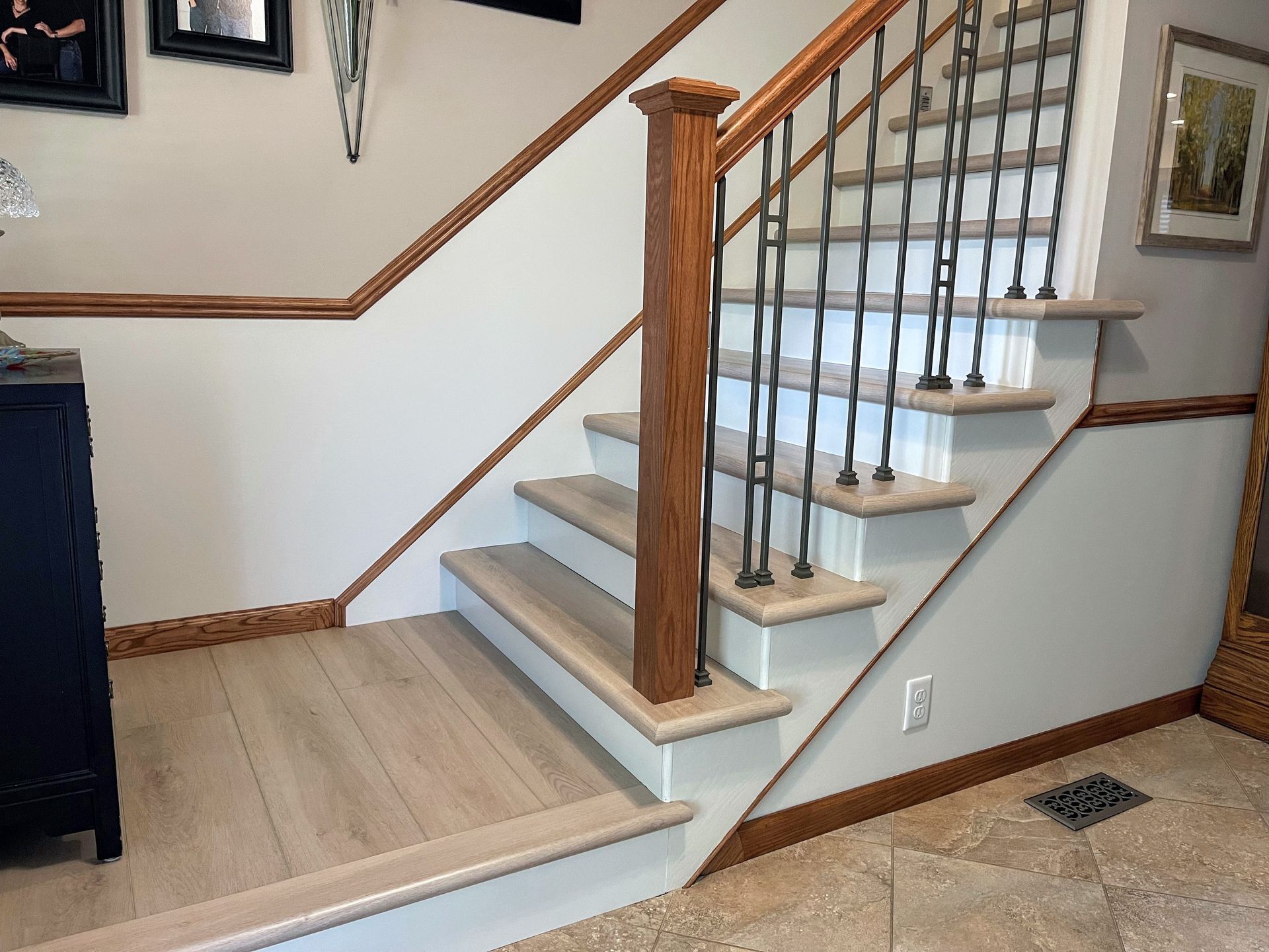 Staircase with light wood steps, white walls, and dark metal railing. Wood trim and post.